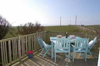 Raised decking area with furniture and bbq to take in the sea views